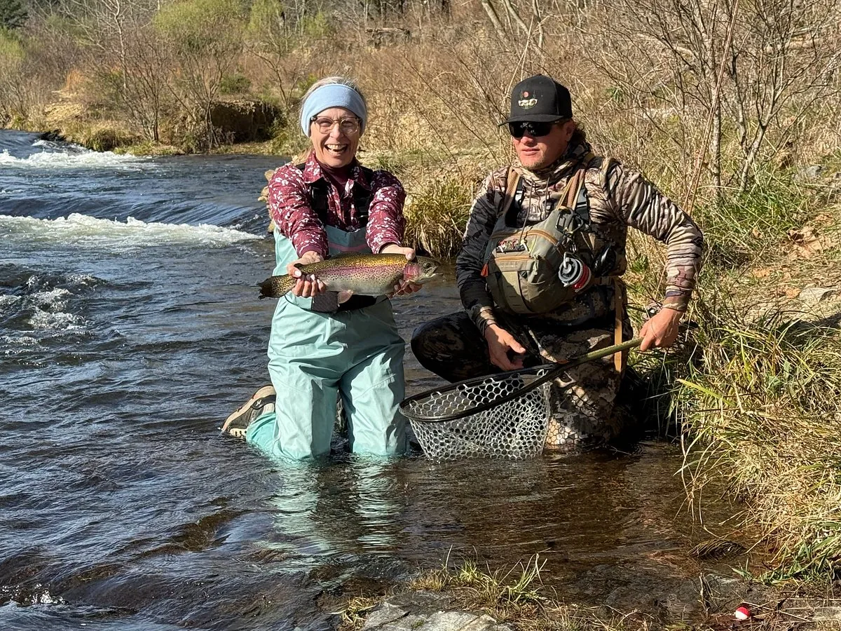 Guided fishing trip client holding a rainbow trout on the Mountain Fork River near Broken Bow