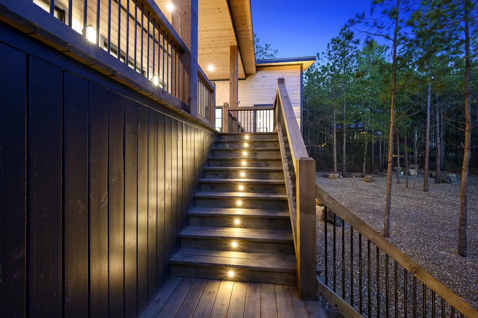Multi-level exterior staircase and illuminated covered decks at The Arcadia at twilight among the pines