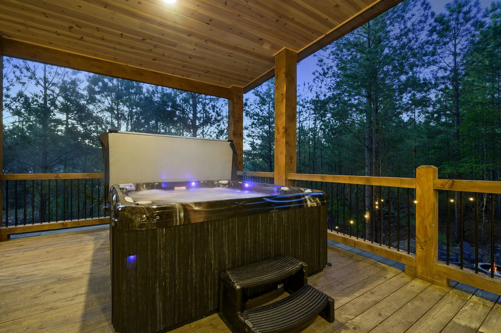 Covered A-frame deck at The Arcadia with wood ceiling, sectional seating, and hot tub visible below