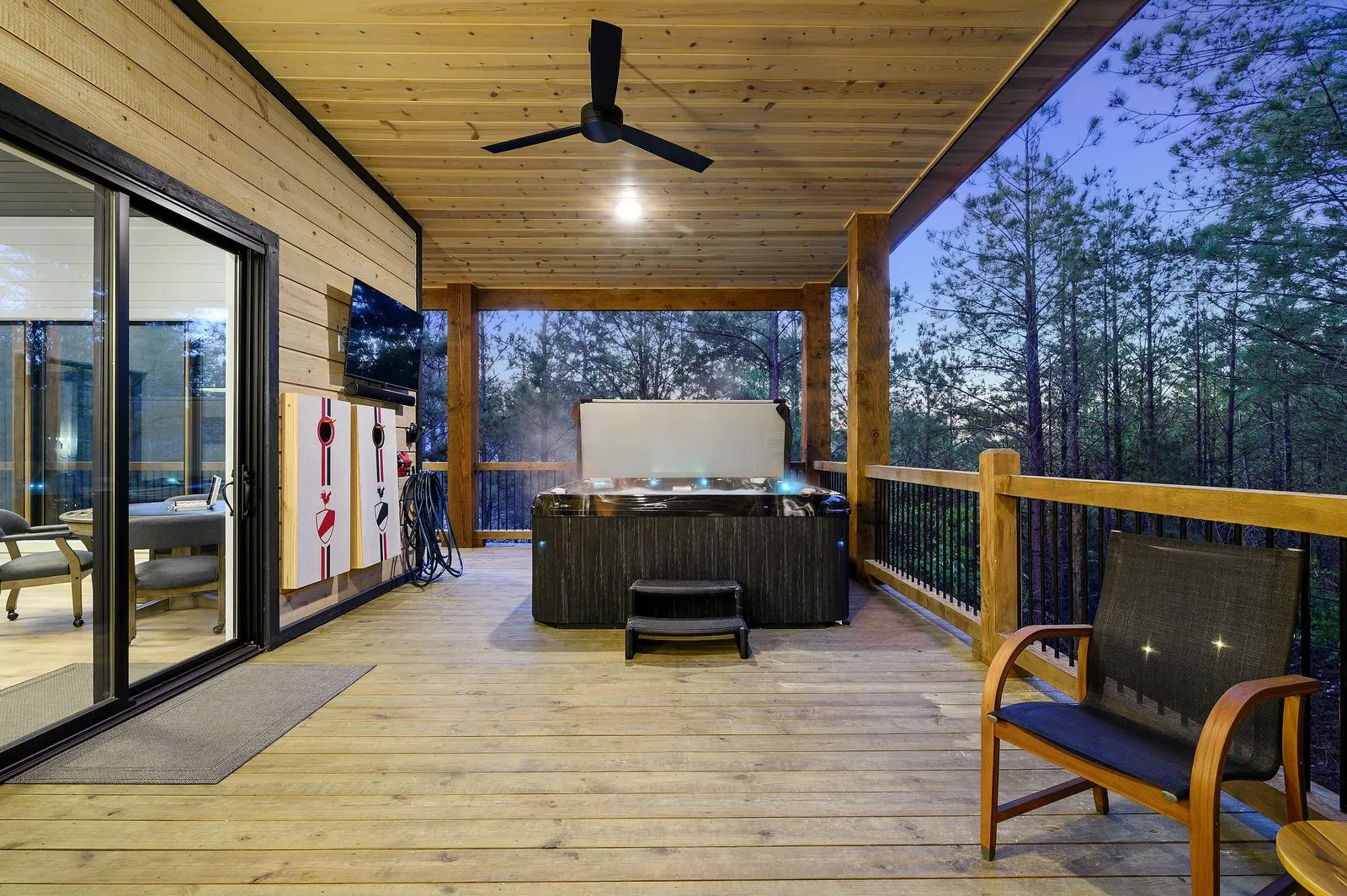 Covered deck overview at The Arcadia with outdoor dining, lounge seating, and hot tub at dusk