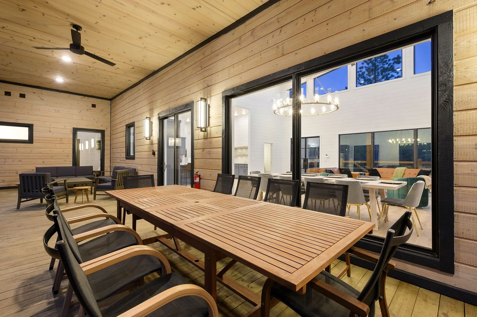 Covered deck with outdoor dining table at The Arcadia and sightline into glass-walled interior