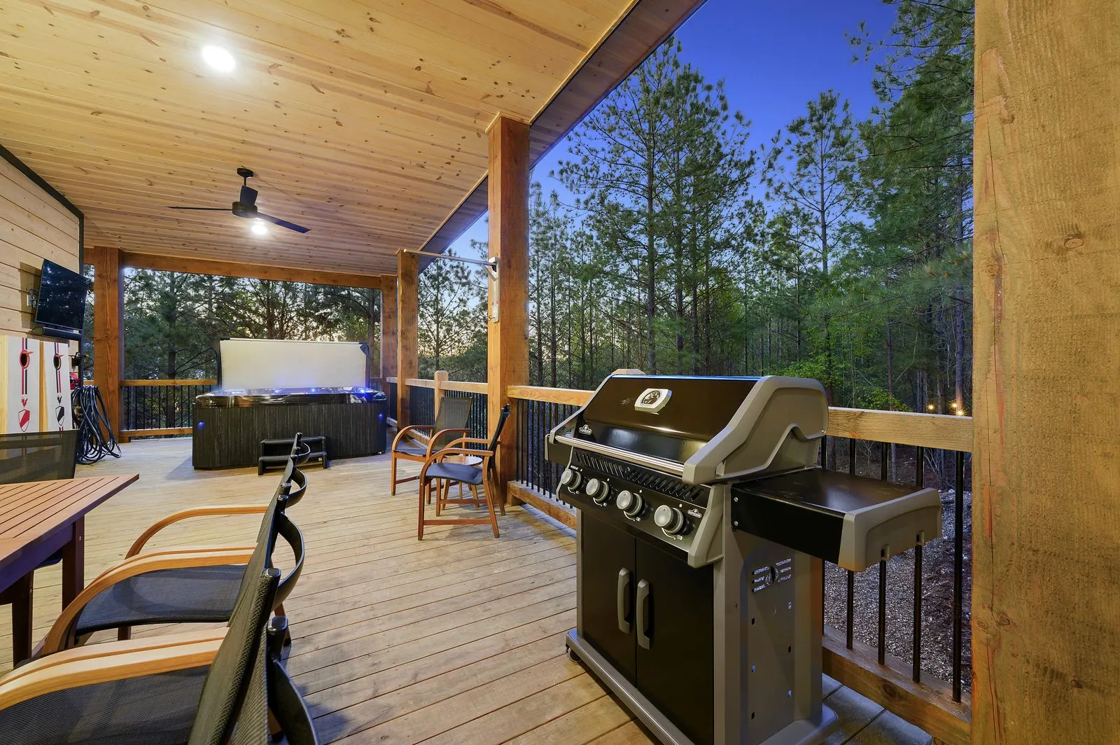 Covered deck at The Arcadia from alternate angle showing outdoor grill and seating area at twilight