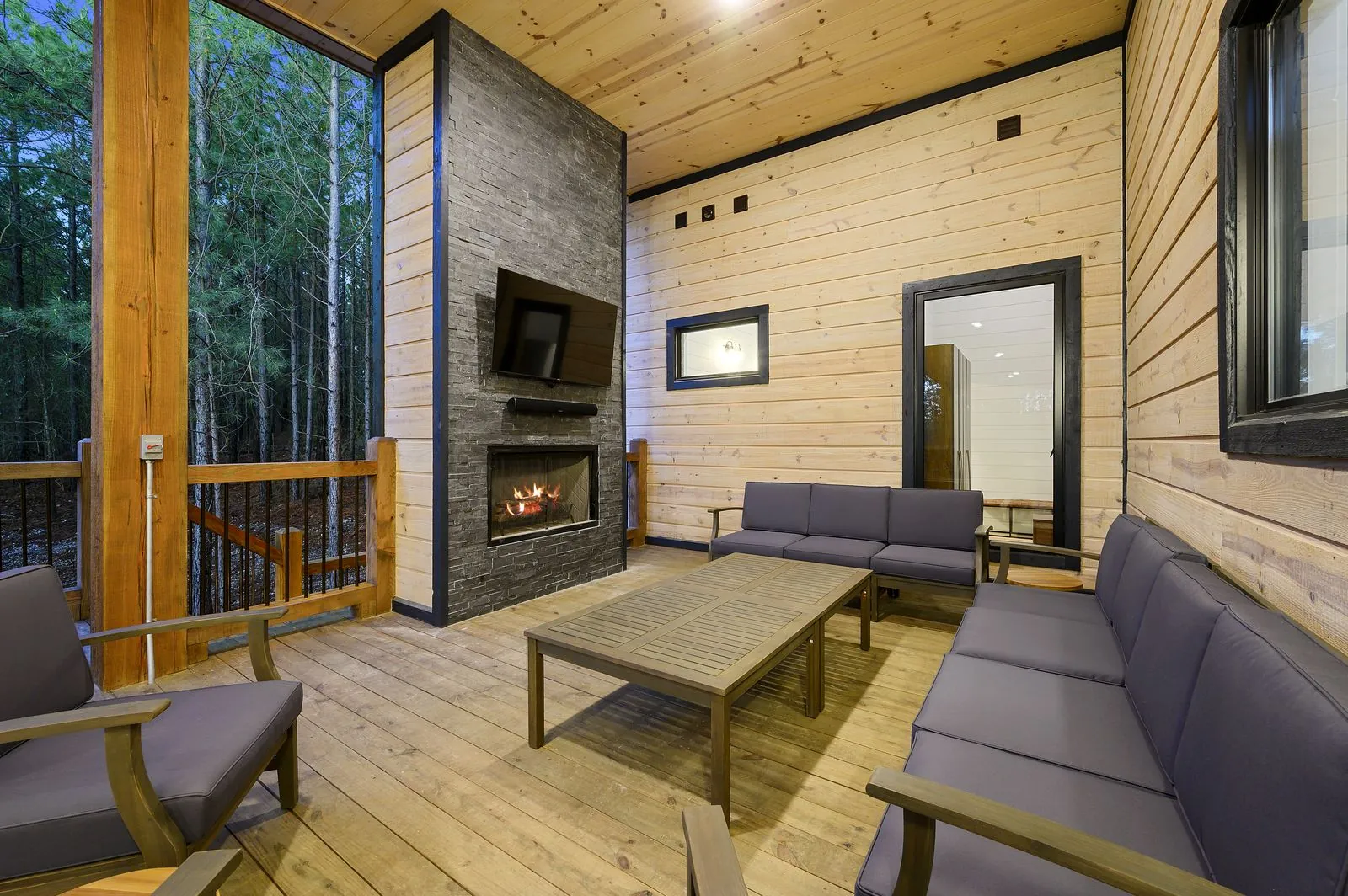 Exterior view looking into The Arcadia living room through windows with chandelier and warm glow at dusk
