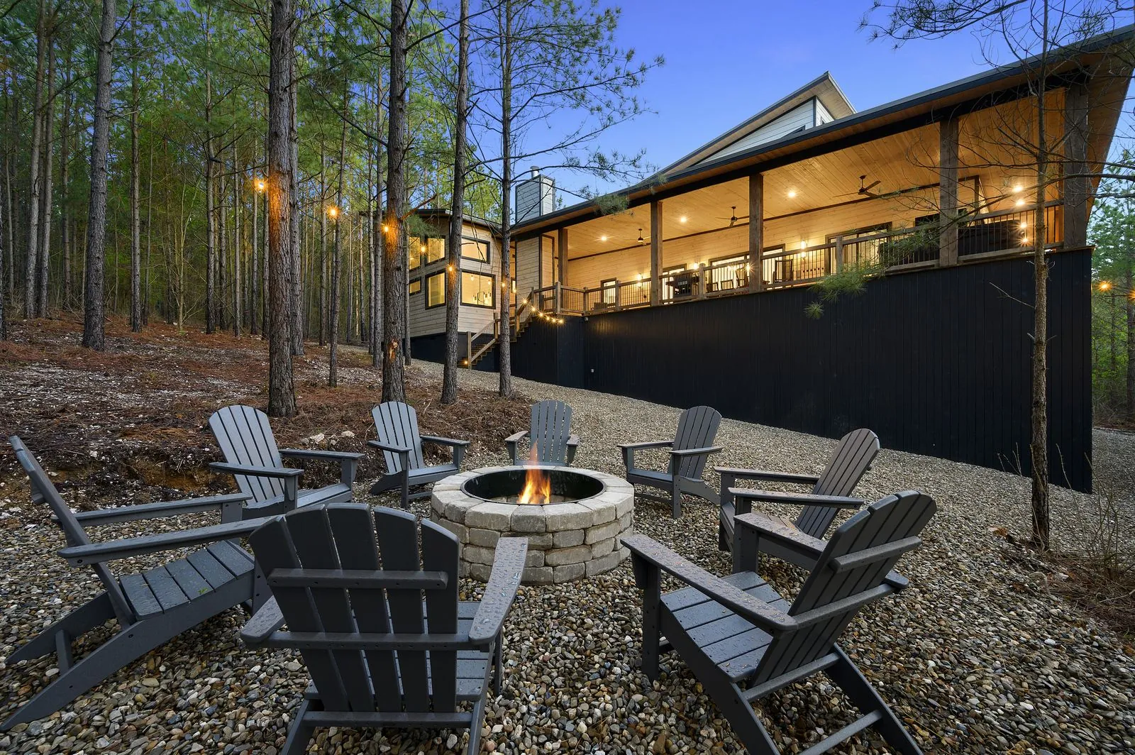 Fire pit area with Adirondack chairs at The Arcadia surrounded by trees at twilight