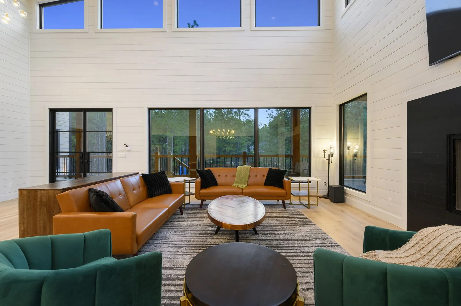 Living room at The Arcadia from alternate angle showing wall-mounted TV, fireplace, and floor-to-ceiling windows