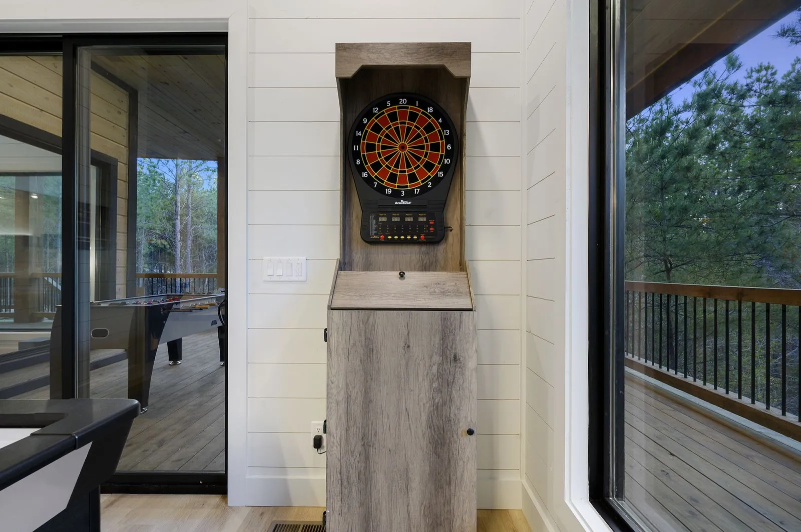 Electronic dartboard mounted on reclaimed wood accent wall at The Arcadia