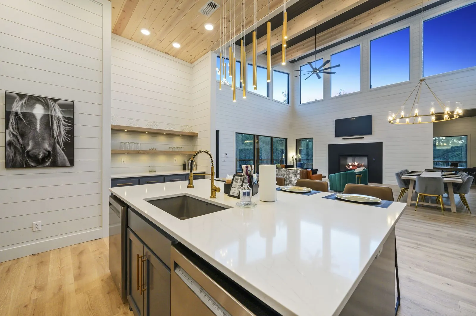 Kitchen at The Arcadia with gray cabinetry, white countertops, brown leather bar stools, and gold pendants
