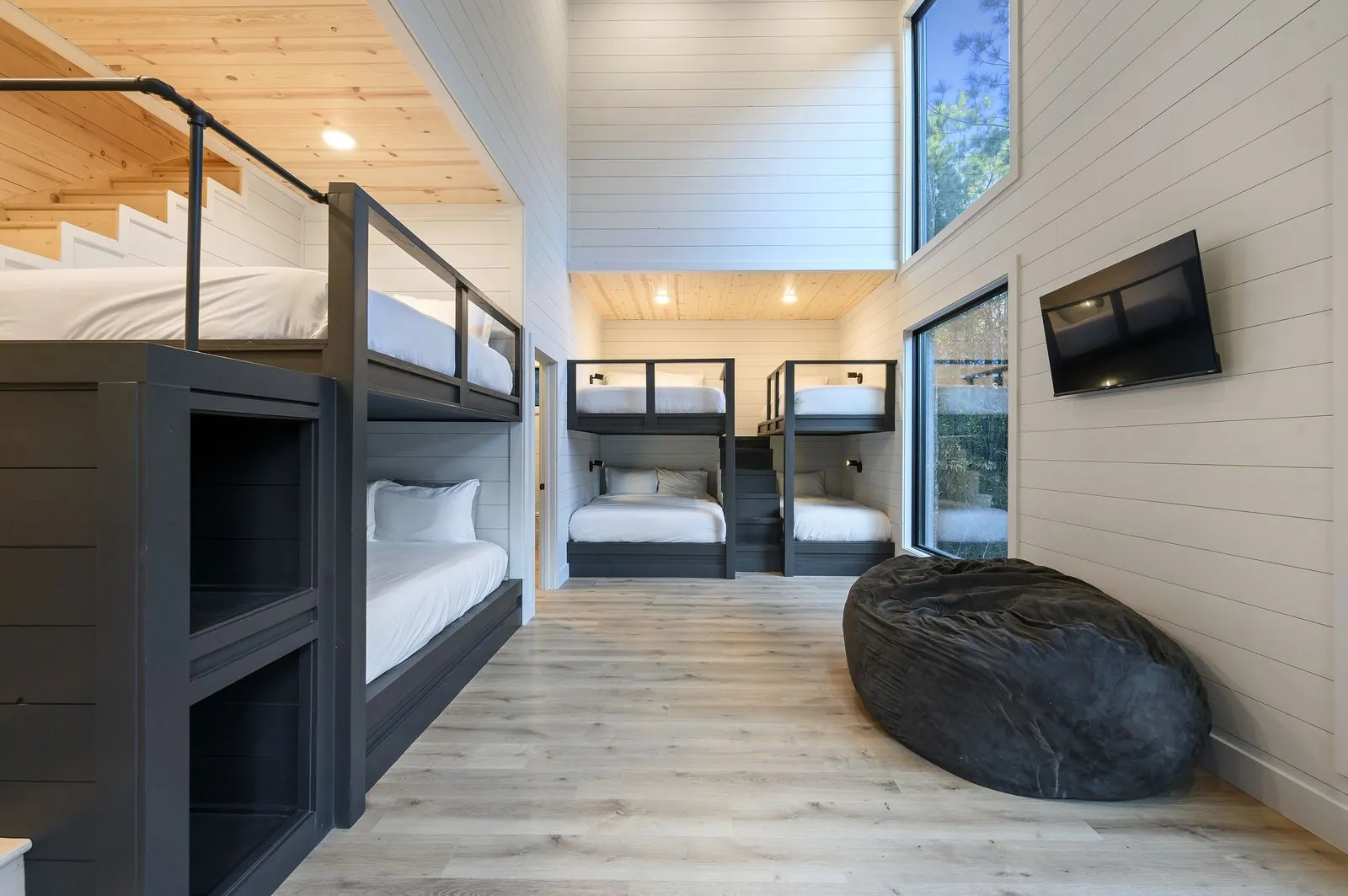 Bunk room at The Arcadia with built-in dark metal frame bunks, wood ceiling, and individual reading lights