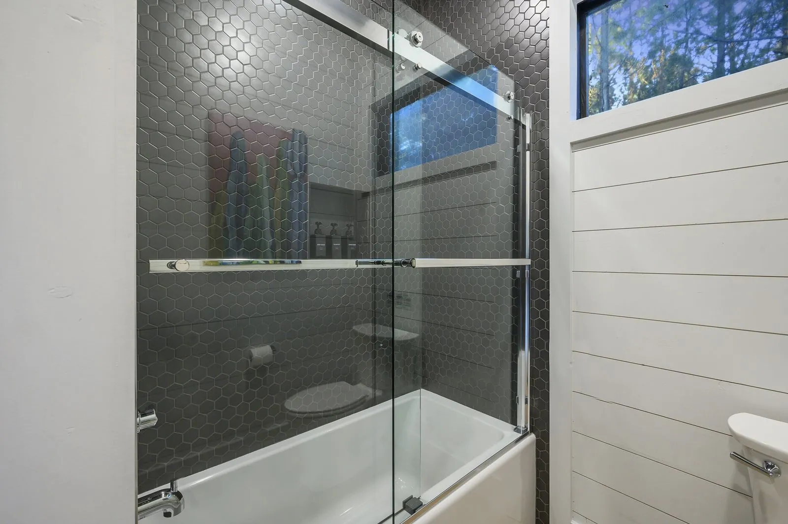 Bathroom at The Arcadia with navy vanity, toilet, and rolled towel display shelf