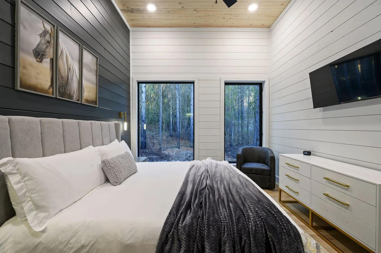 King bedroom at The Arcadia with warm wood vaulted ceiling, pendant lights, and cozy bedding