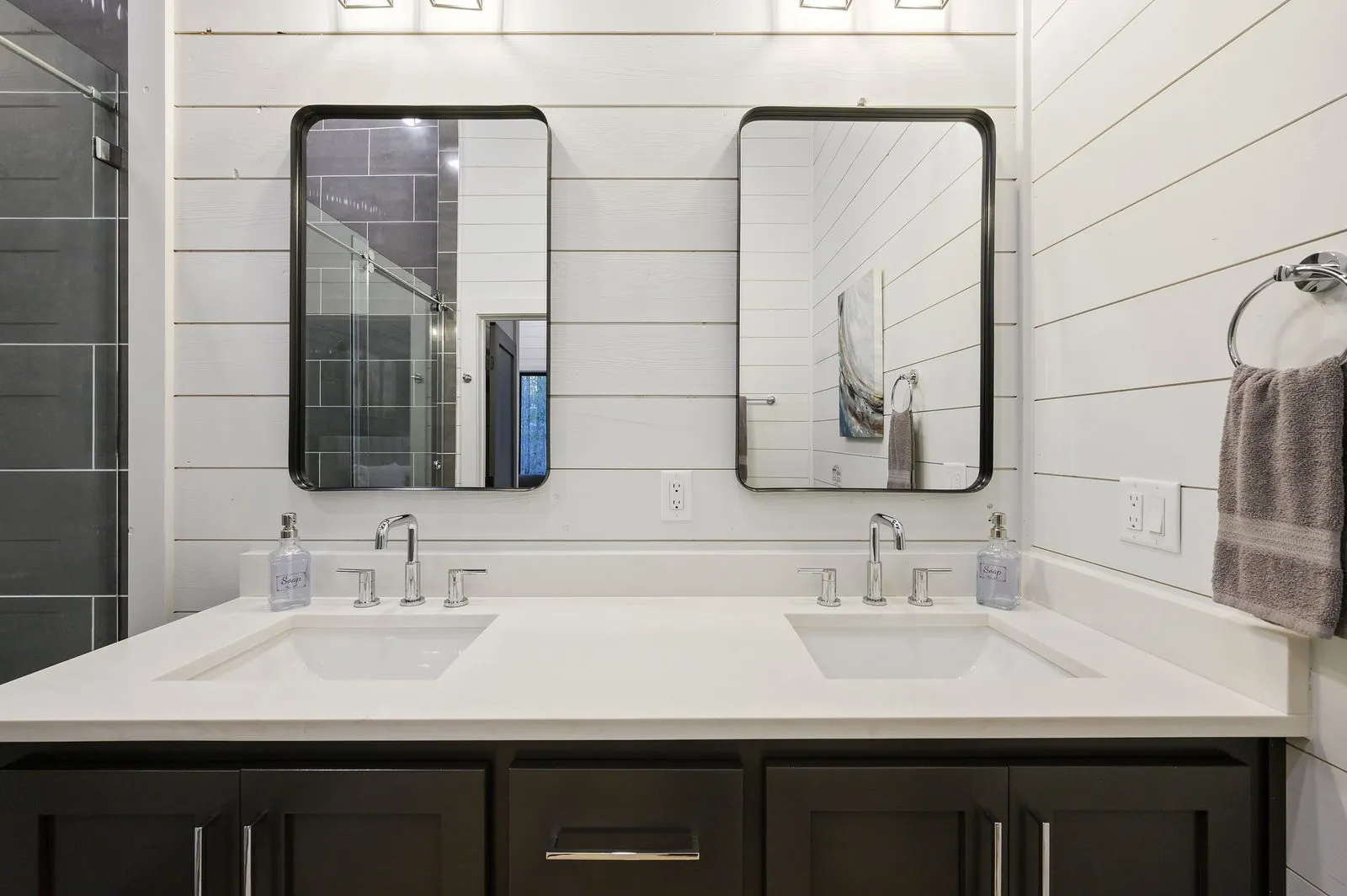 Walk-in shower at The Arcadia with dark marble tile walls, glass door, and mosaic pebble floor