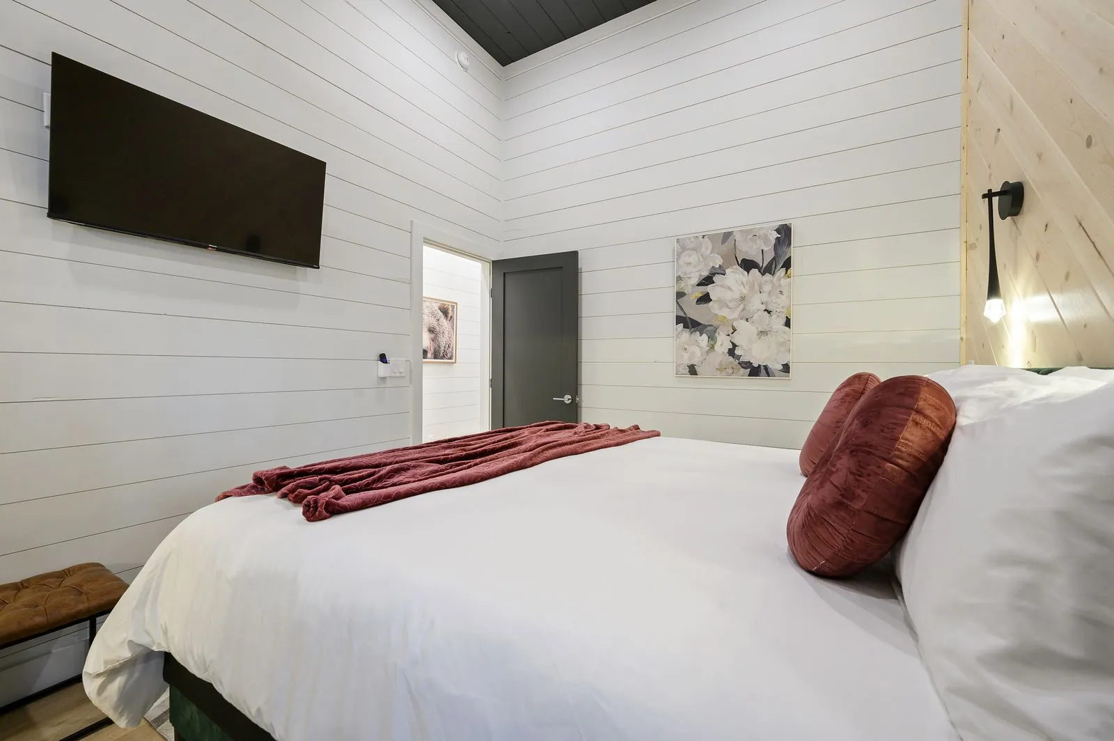King bedroom at The Arcadia from wider angle showing green accent wall, wood ceiling, and ceiling fan