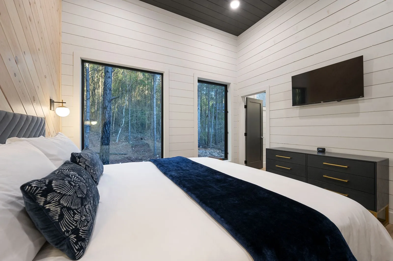 Bathroom at The Arcadia with navy vanity, walk-in shower with marble tile, and pebble floor accent