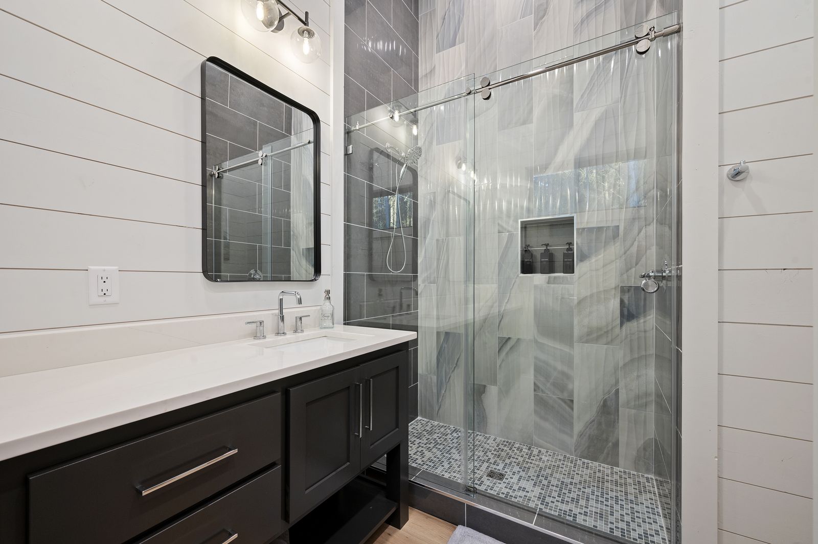 Bathroom vanity at The Arcadia with dark cabinets, dual undermount sinks, and large framed mirror