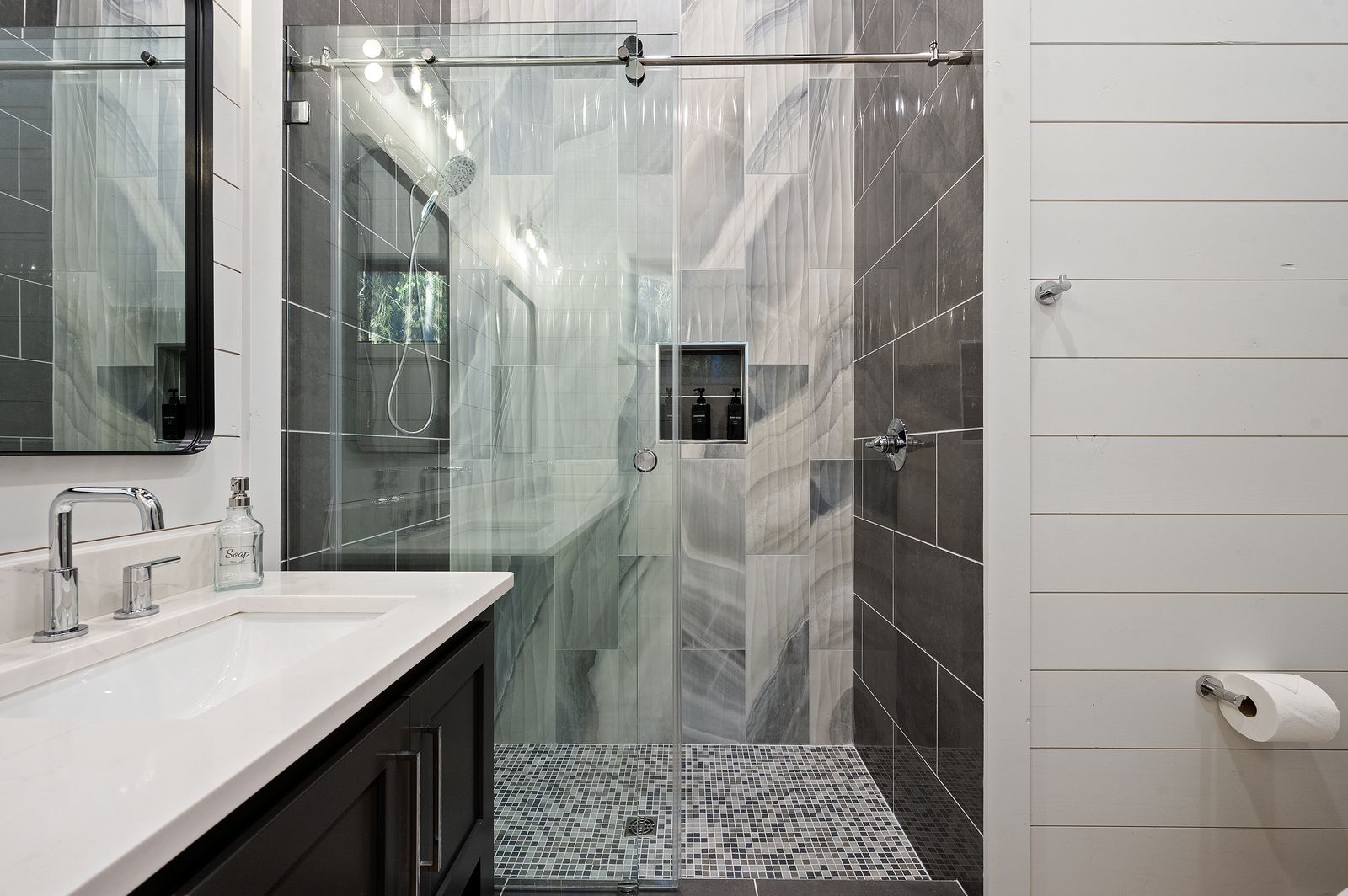 Walk-in shower with dual showerheads and dark marble swirl tile at The Arcadia from alternate angle