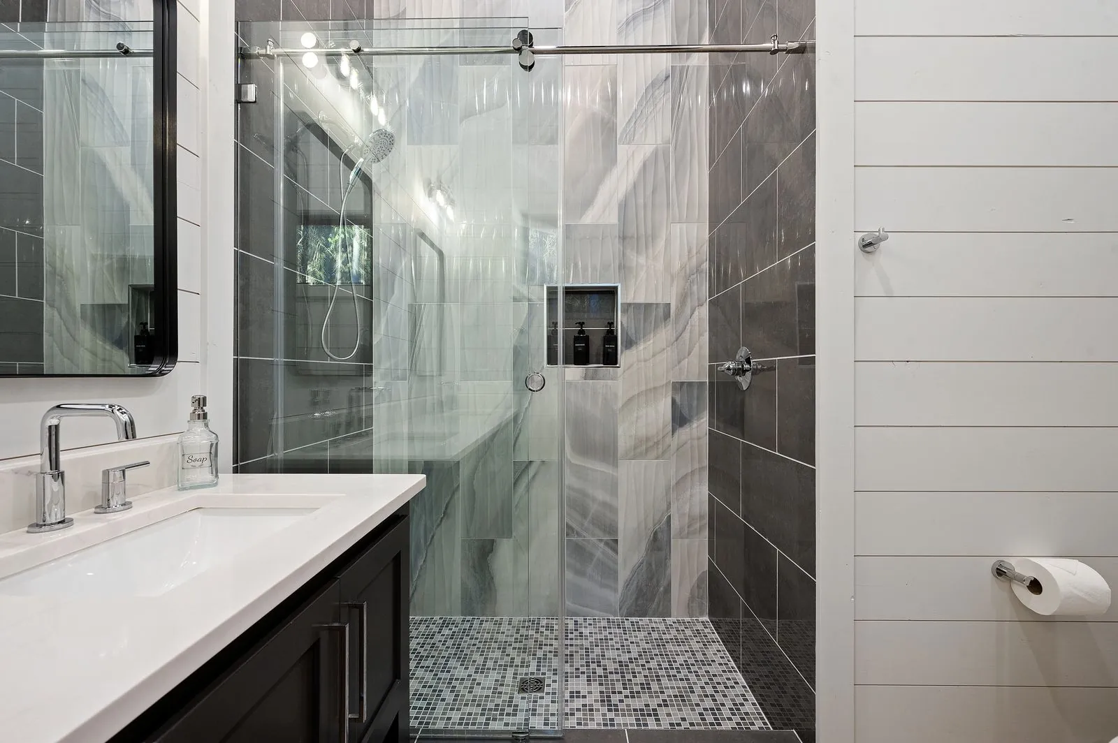 Walk-in shower with dual showerheads and dark marble swirl tile at The Arcadia from alternate angle