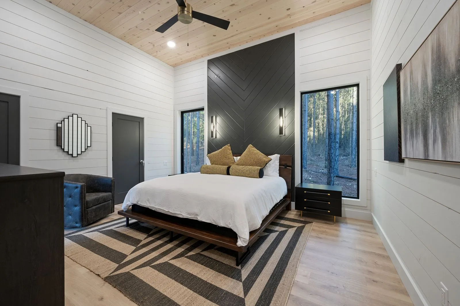 King bedroom at The Arcadia with white shiplap walls, TV, dark accent panels, and vaulted ceiling