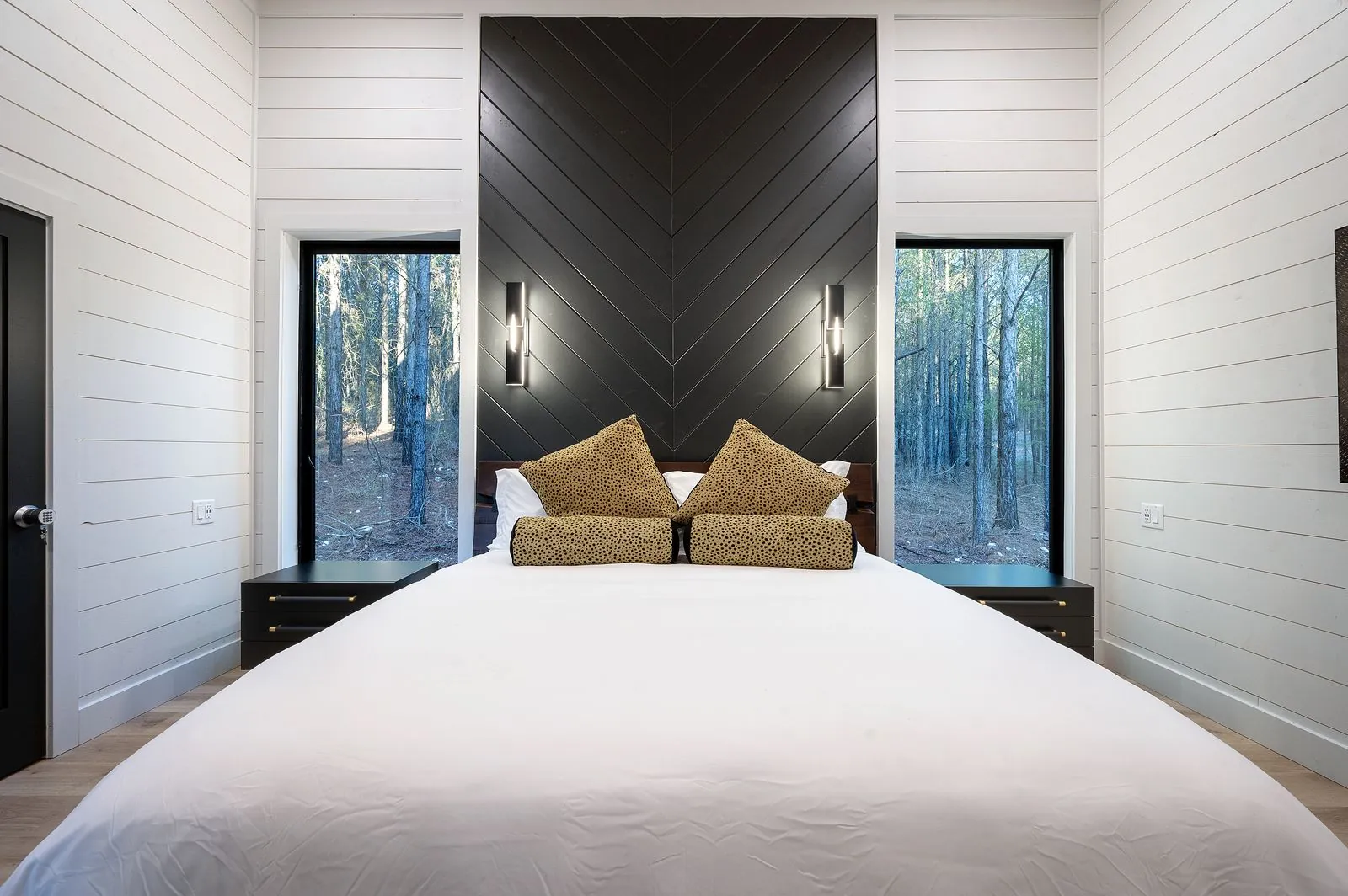 King bedroom at The Arcadia with navy bedding, gold accent pillows, and dark chevron accent wall