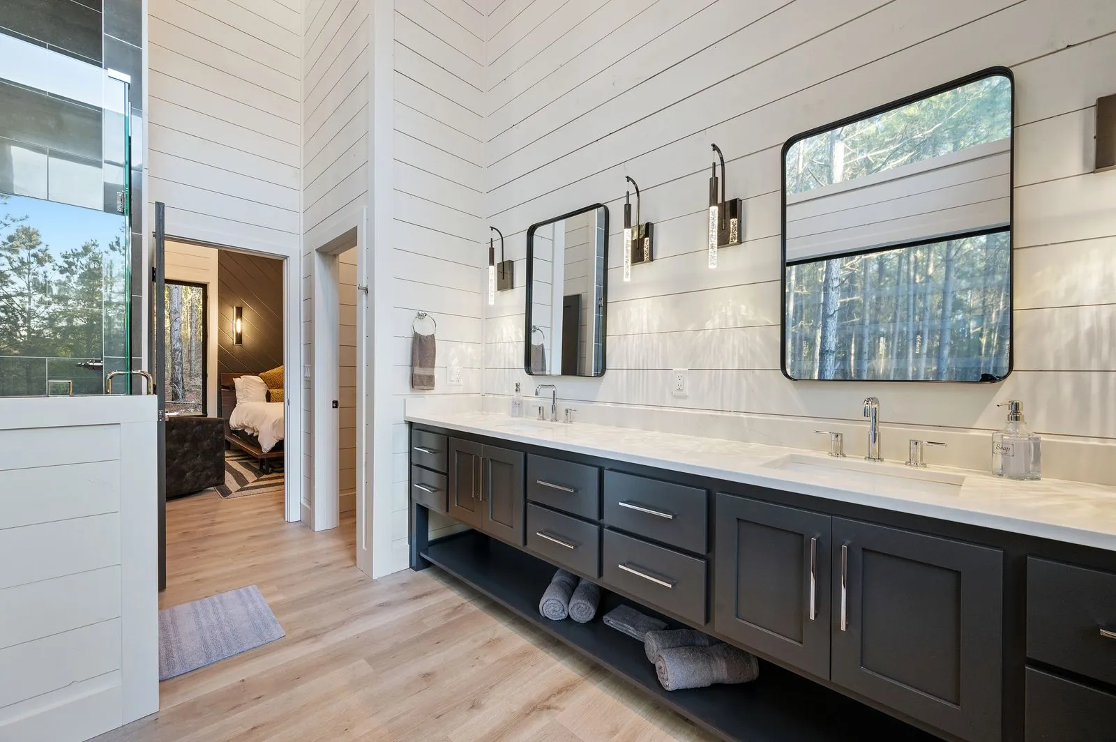 Freestanding soaking tub at The Arcadia primary bathroom with large picture windows overlooking the forest