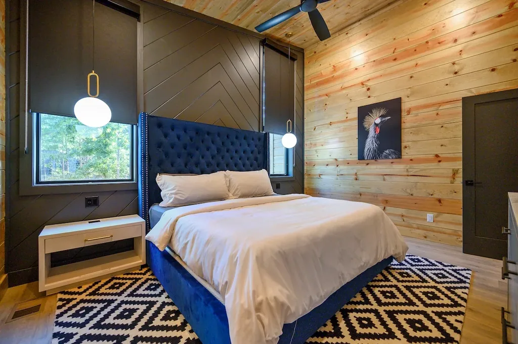 King Bedroom 1 with blue tufted headboard and forest-view windows