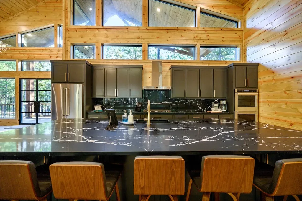 Chef's kitchen with black marble island and wood counter stools