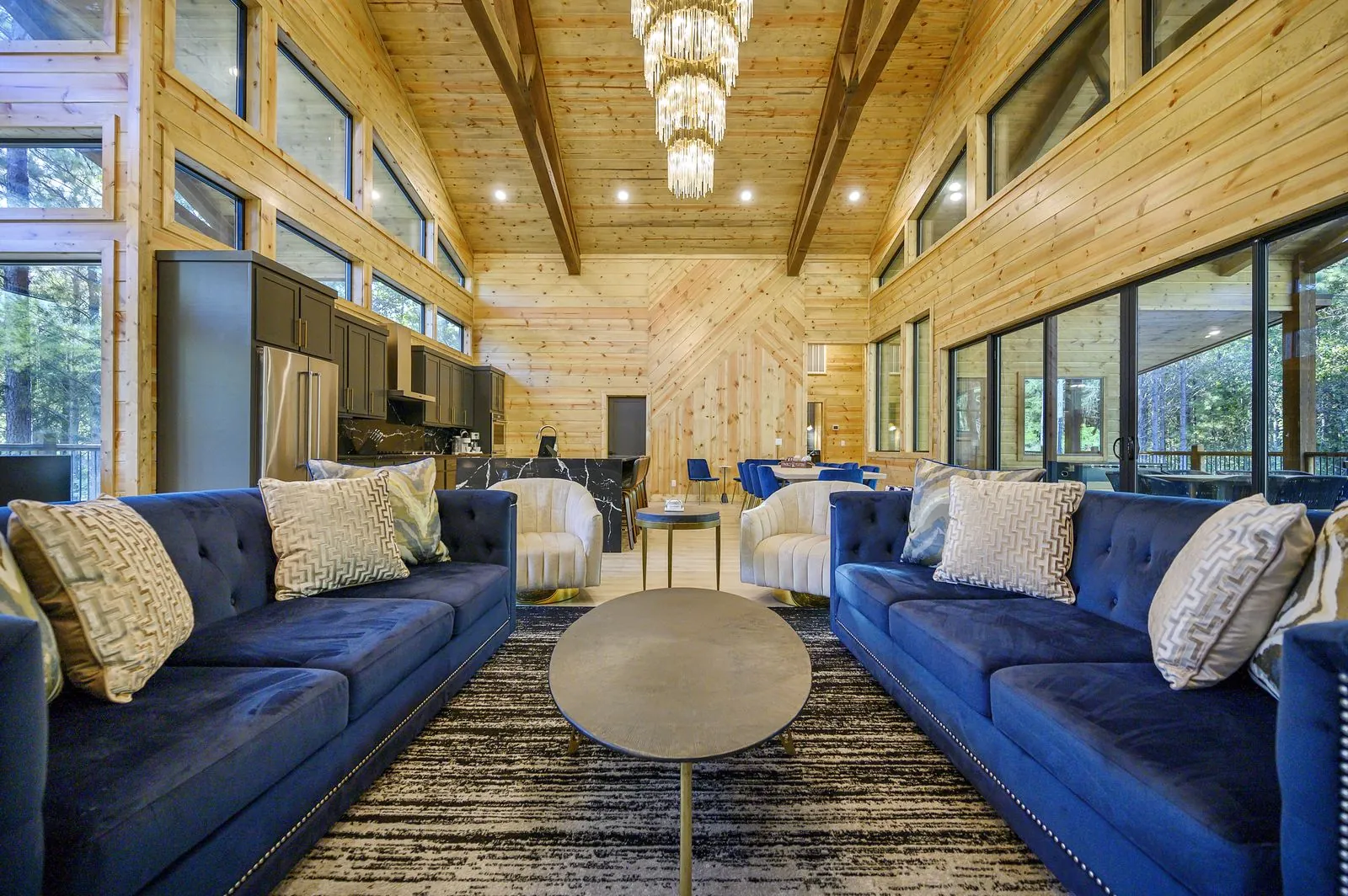 Guests conversing on blue velvet sectional sofas in The Avalon great room with crystal pendant chandeliers