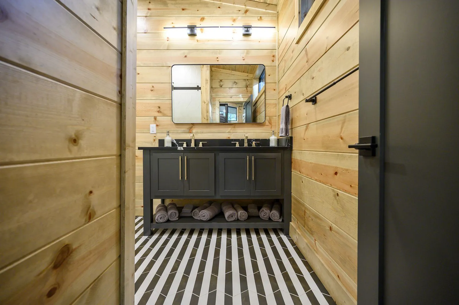 Bunk room at The Avalon with metal-frame bunk beds, gray bedding, and forest views through windows