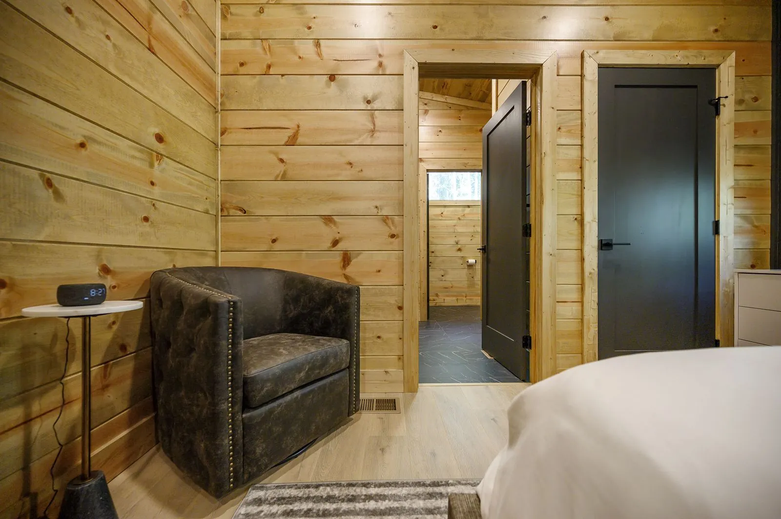 King bedroom at The Avalon with dark accent wall, ceiling fan, and warm wood paneling