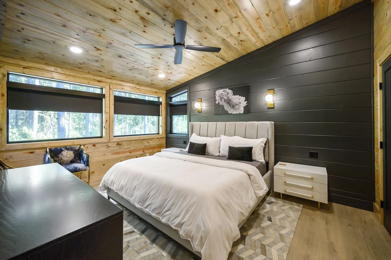 Bedroom at The Avalon with king bed, gray headboard, amber pillow, and ceiling fan