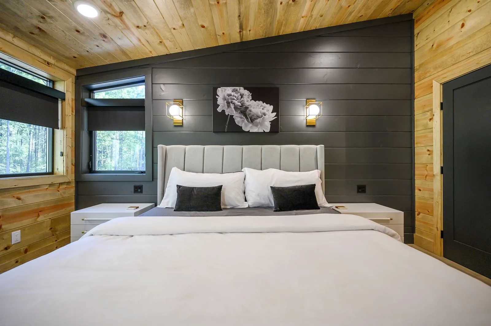 Master bedroom at The Avalon with king bed, gray headboard, reading light, and dark leather accent chair