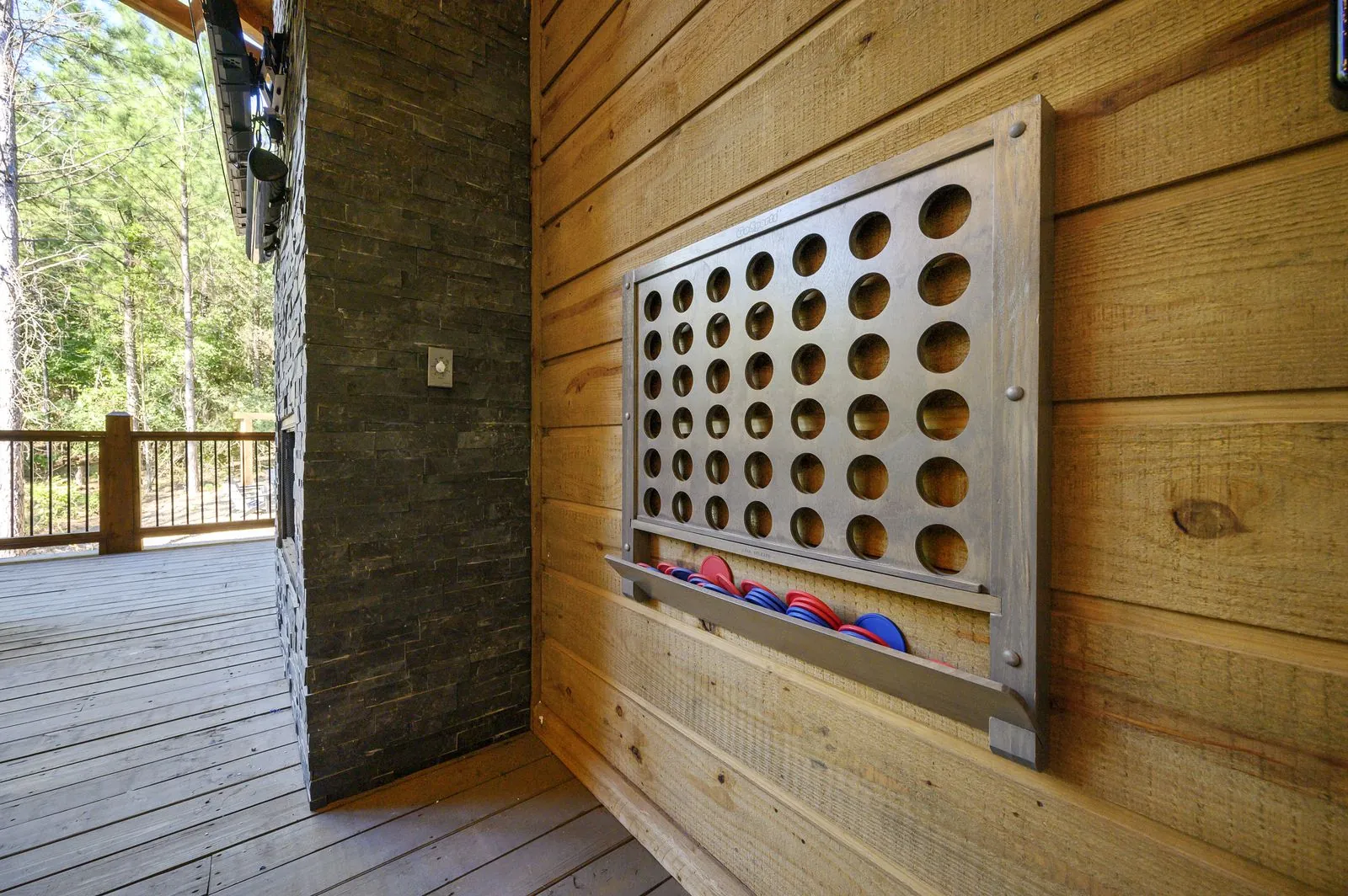 Covered outdoor deck at The Avalon with foosball table and forest views through screened porch
