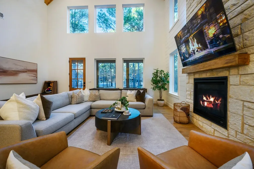 The Black-Beary — Living room with a stone gas fireplace, mounted TV, and a sectional sofa and leather armchairs arranged around a round coffee table.