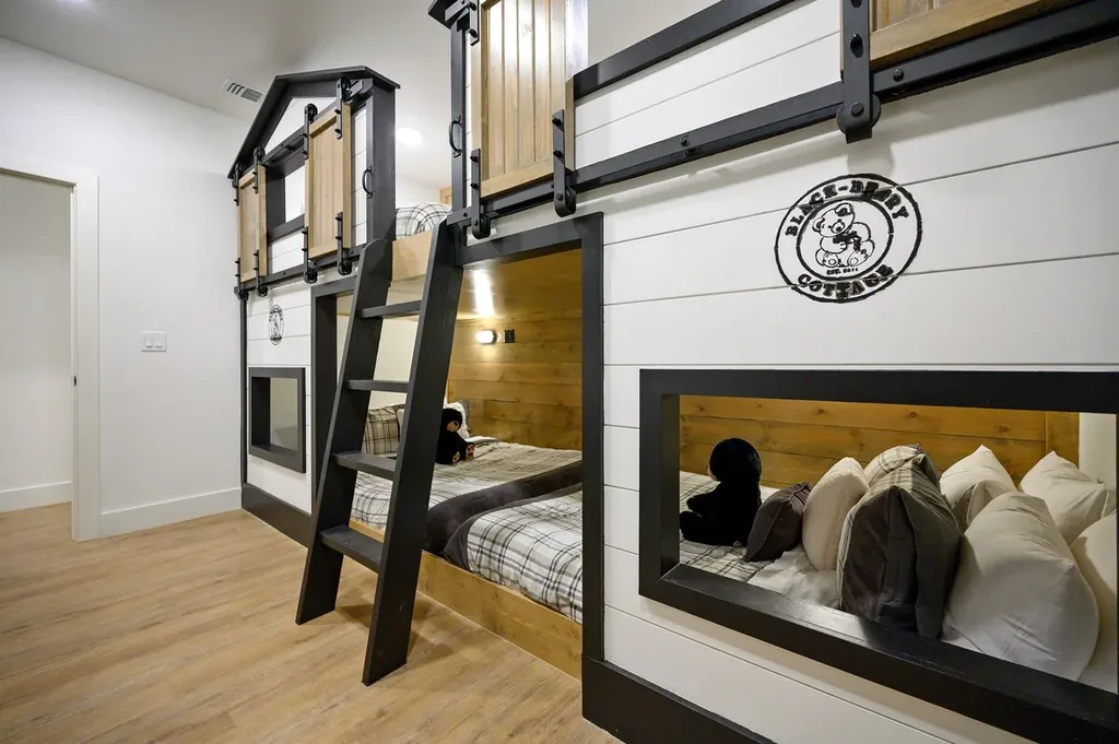 The Black-Beary — Custom carved-out bunks with barn-door detailing and plush pillows give kids and groups their own cozy corner to sleep.