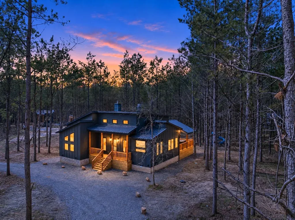 Blue Note — Tucked into the pines with private driveway parking for 3 to 4 vehicles, this cabin glows warmly against the Oklahoma sunset.