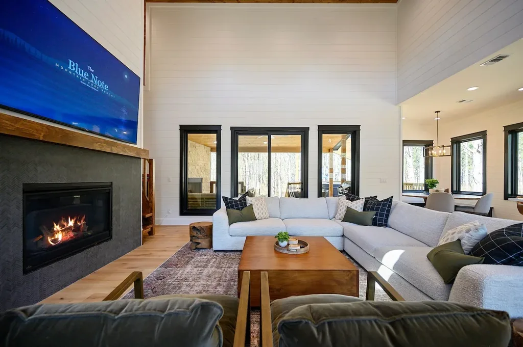 Blue Note — The open-concept living area has a gas fireplace, a smart TV, and a large sectional with high ceilings overhead. Sliding glass doors lead out to the private outdoor living space.