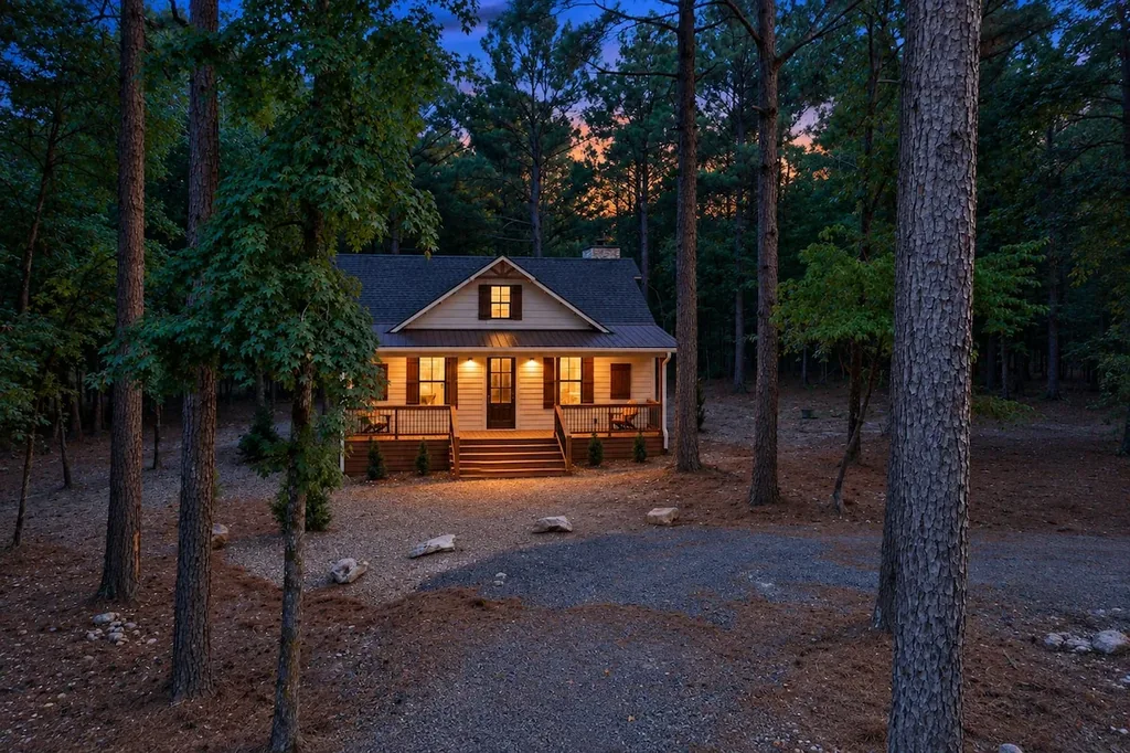Dolce Far Nient — Tucked among tall pines, this cabin's lit porch and gravel drive offer a quiet, private retreat at day's end.