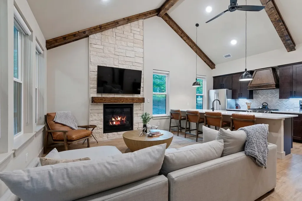 Dolce Far Nient — High vaulted beam ceilings and a stone fireplace anchor a living space that opens straight into the kitchen bar, made for gathering.