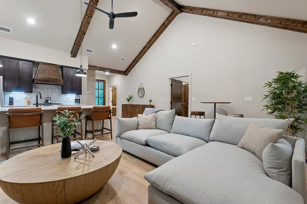 Dolce Far Nient — Sink into the oversized sectional in a living room framed by soaring wood-beam ceilings and open sightlines to the kitchen.