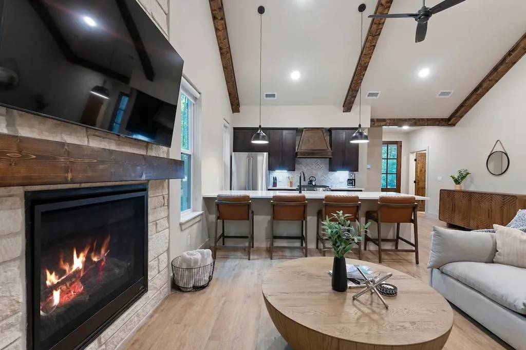 Dolce Far Nient — Gather by the stone fireplace or pull up a stool at the island, all within one open living and kitchen space under vaulted wood-beamed ceilings.