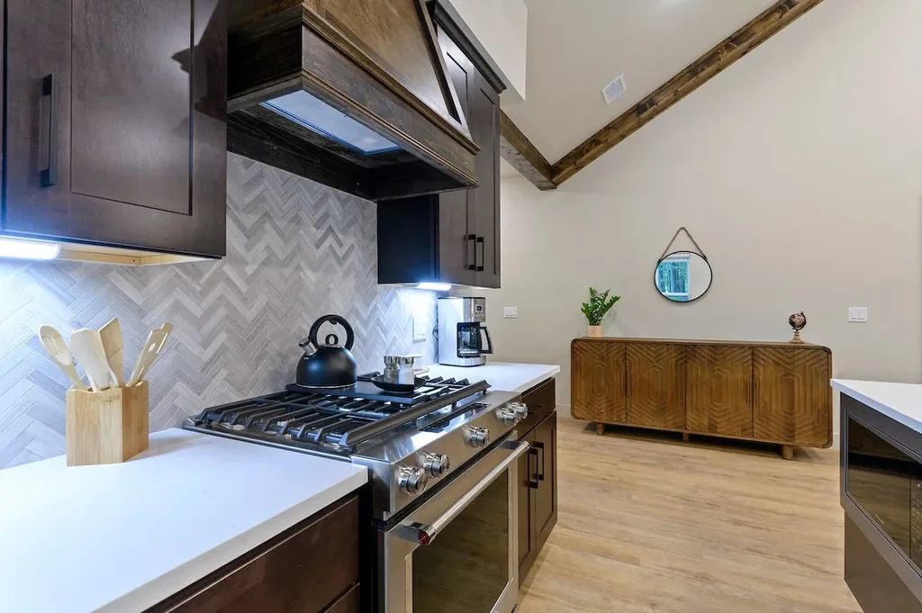 Dolce Far Nient — Cook on a professional-style gas range in a kitchen designed with custom tile and soaring wood-beamed ceilings.