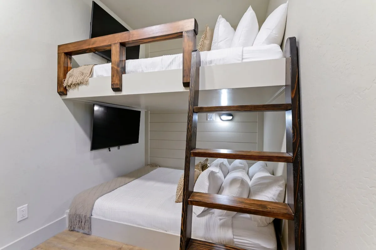 Dolce Far Nient — This bunk room has a queen bed on the bottom and another queen bed on top, each with its own mounted TV and a wooden ladder for access.