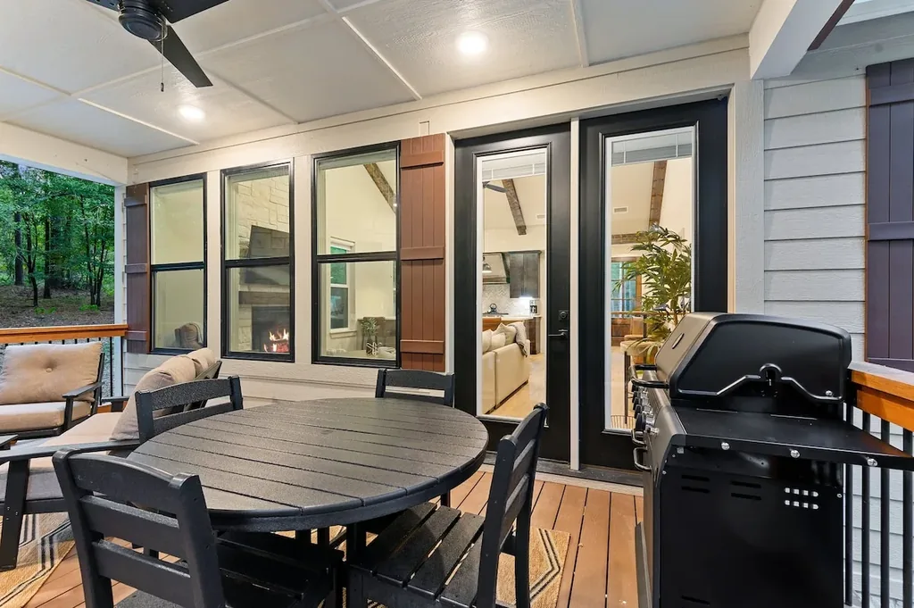 Dolce Far Nient — Covered patio with a round dining table for four and a gas grill, opening through glass doors into the living room.
