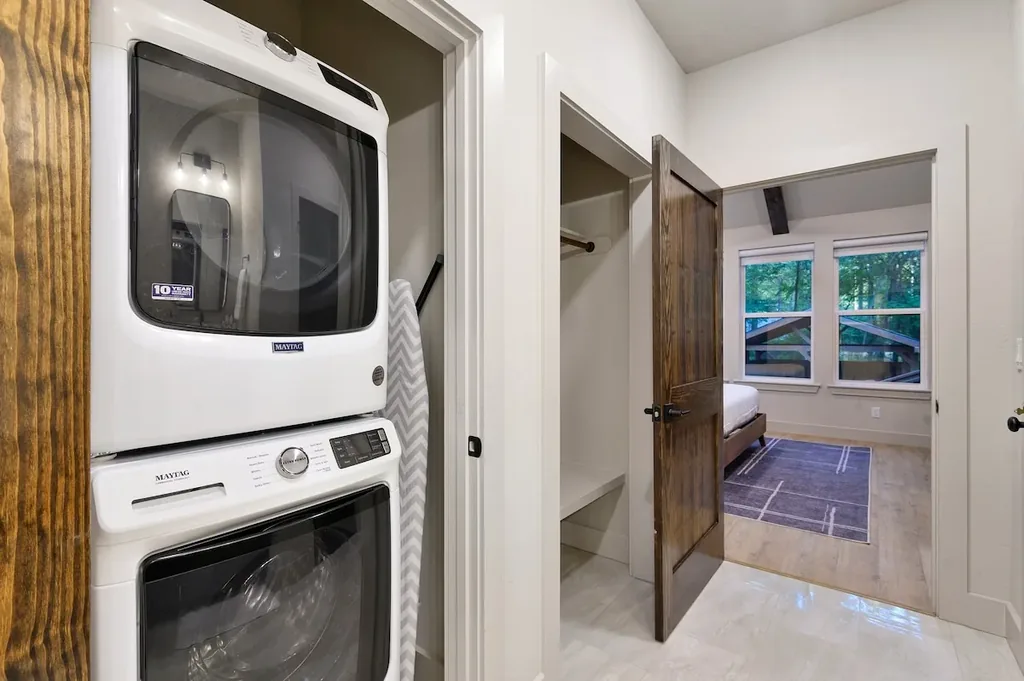 Dolce Far Nient — A stacked Maytag washer and dryer sit in a private laundry closet, with an adjoining walk-in closet leading into the bedroom.