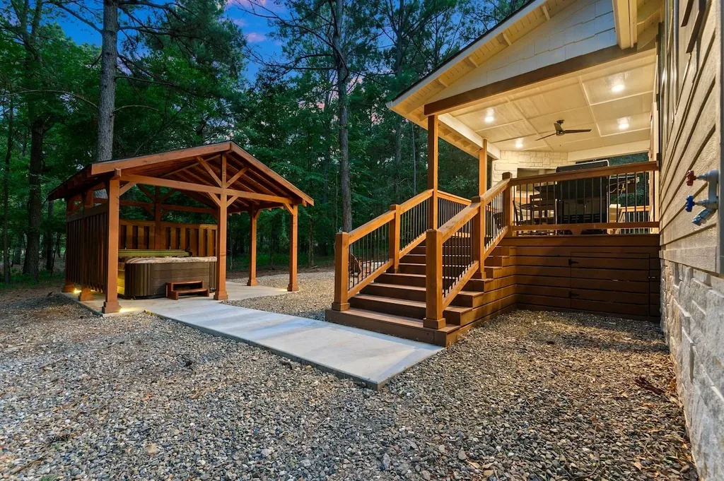 Dolce Far Nient — A private hot tub sits under its own covered wooden pavilion in the backyard, with a lit pathway connecting it to the back deck stairs.
