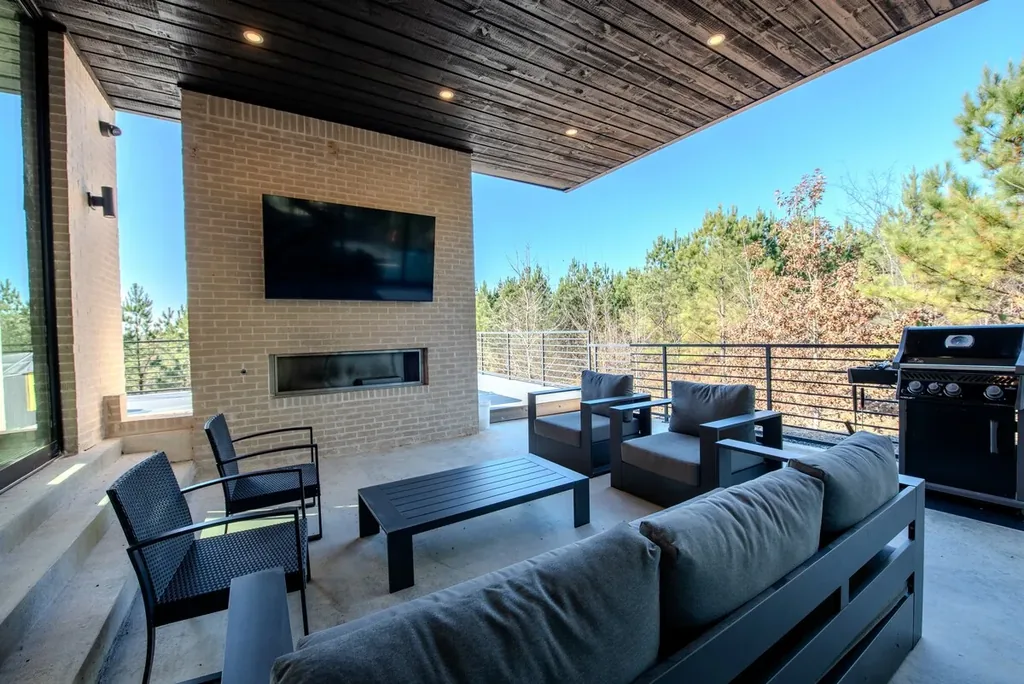 Covered outdoor living area with fireplace, television, and grill