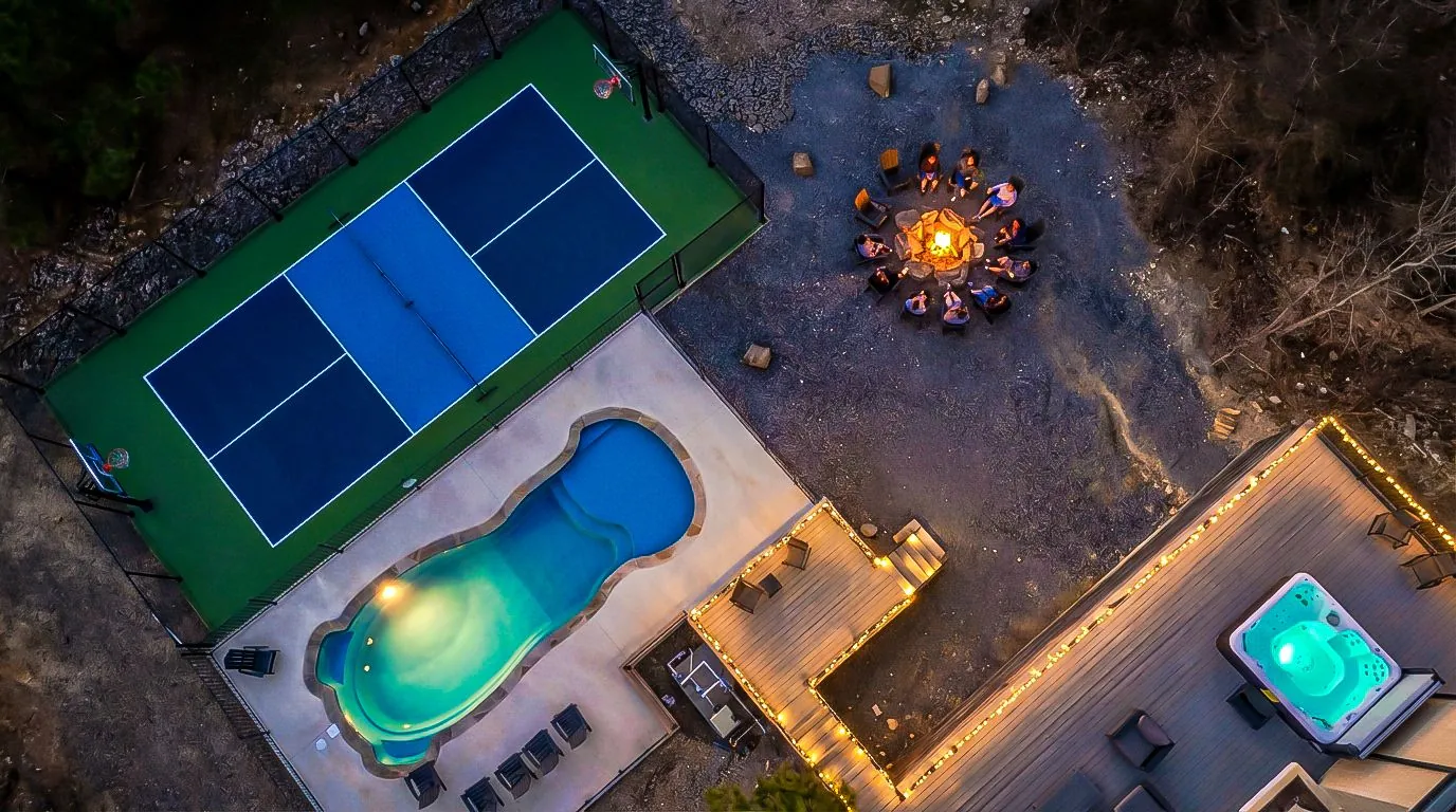Aerial drone view of the private pickleball court, heated pool, and hot tub at The Jade in Broken Bow