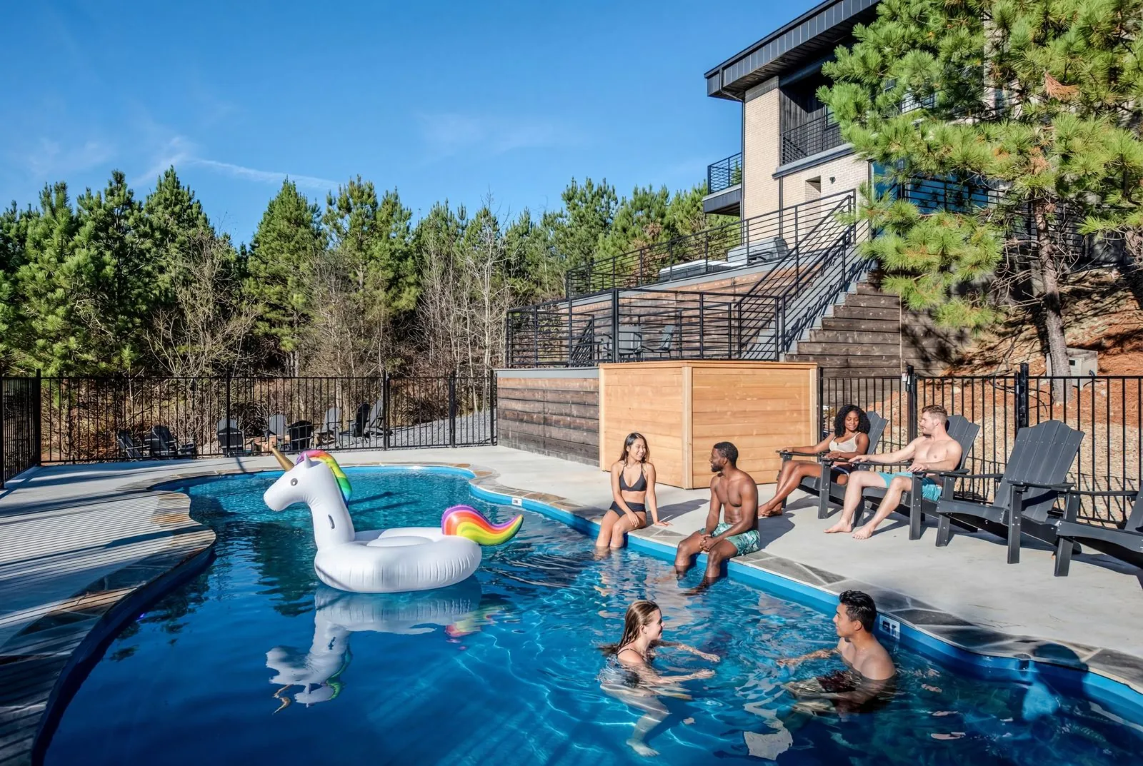 Guests enjoying the heated outdoor pool at The Jade with pool floats and pine forest backdrop