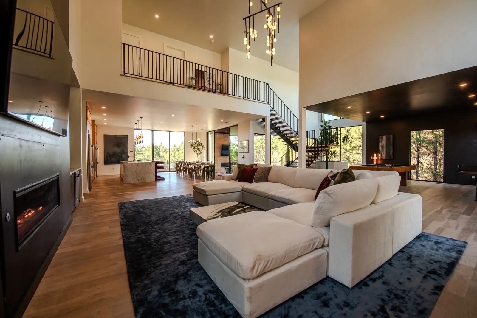 Open-concept great room at The Jade with vaulted ceilings, designer chandelier, and plush sectional