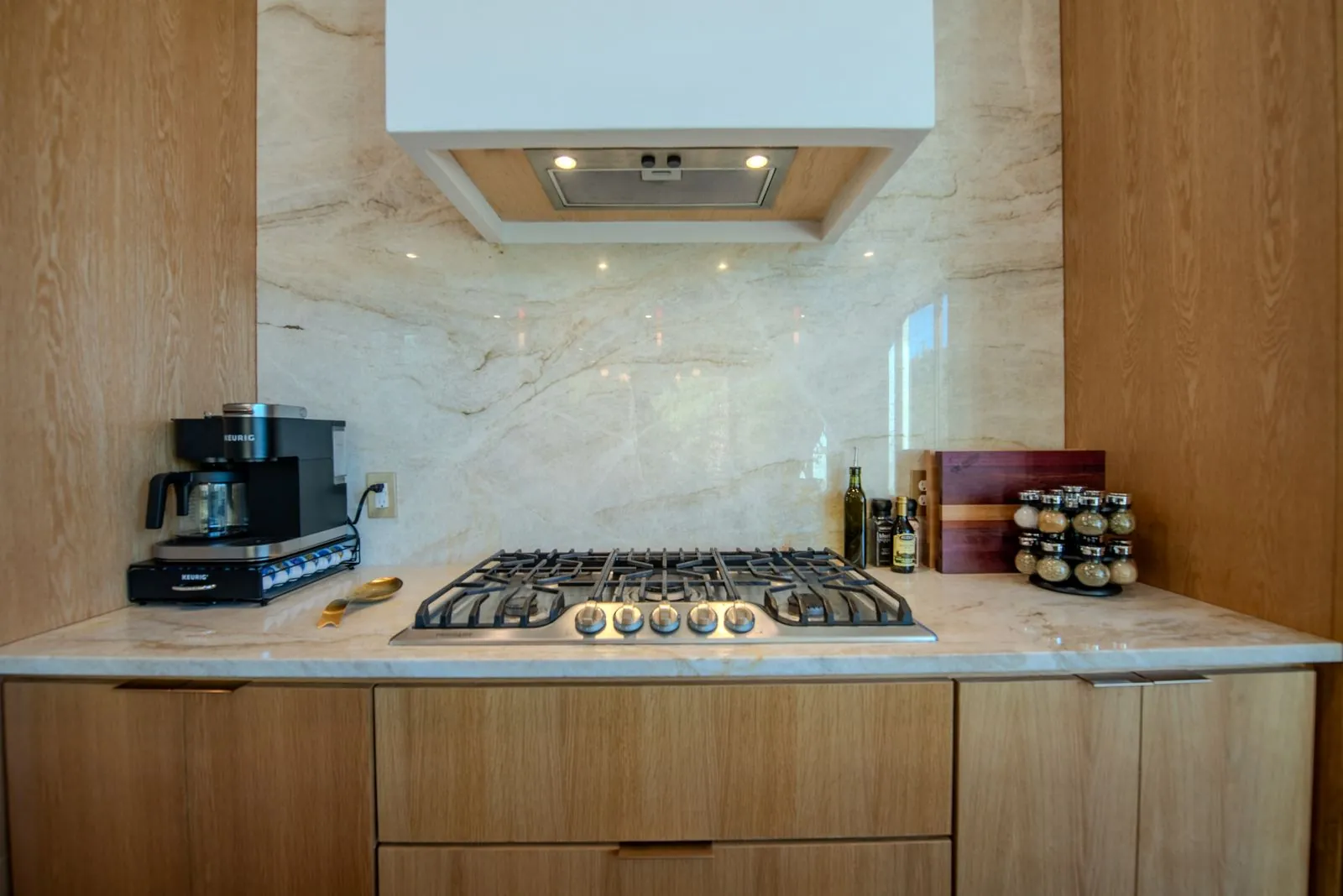 Gas cooktop with marble countertop, professional range hood, and coffee bar at The Jade kitchen
