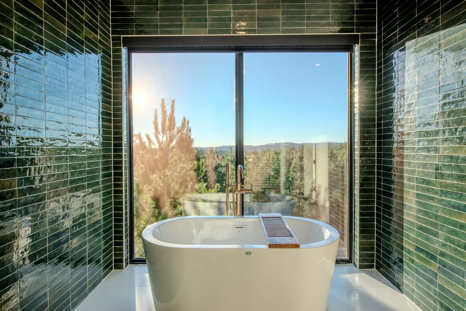 Walk-in rainfall shower at The Jade with green mosaic tile walls and elegant chandelier lighting fixture
